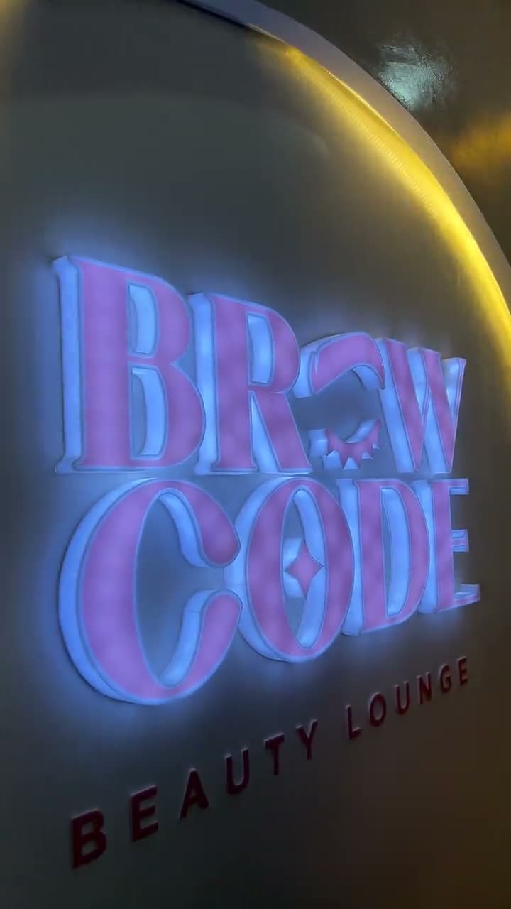 Illuminated Brow Code Beauty Lounge sign inside the lounge